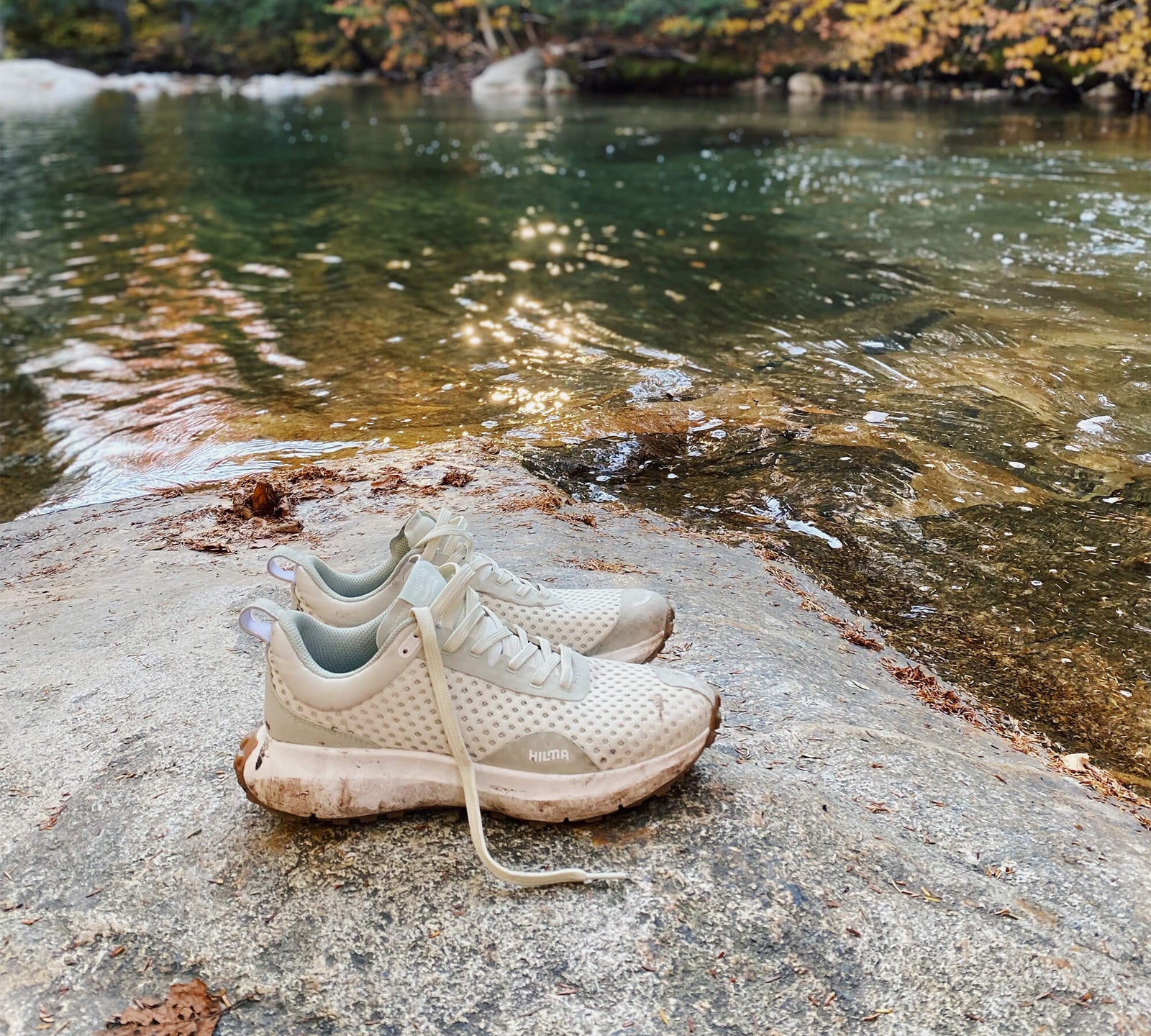 A pair of the Everywhere Frozen Dew Hilma Running shoes on a rock near a body of water