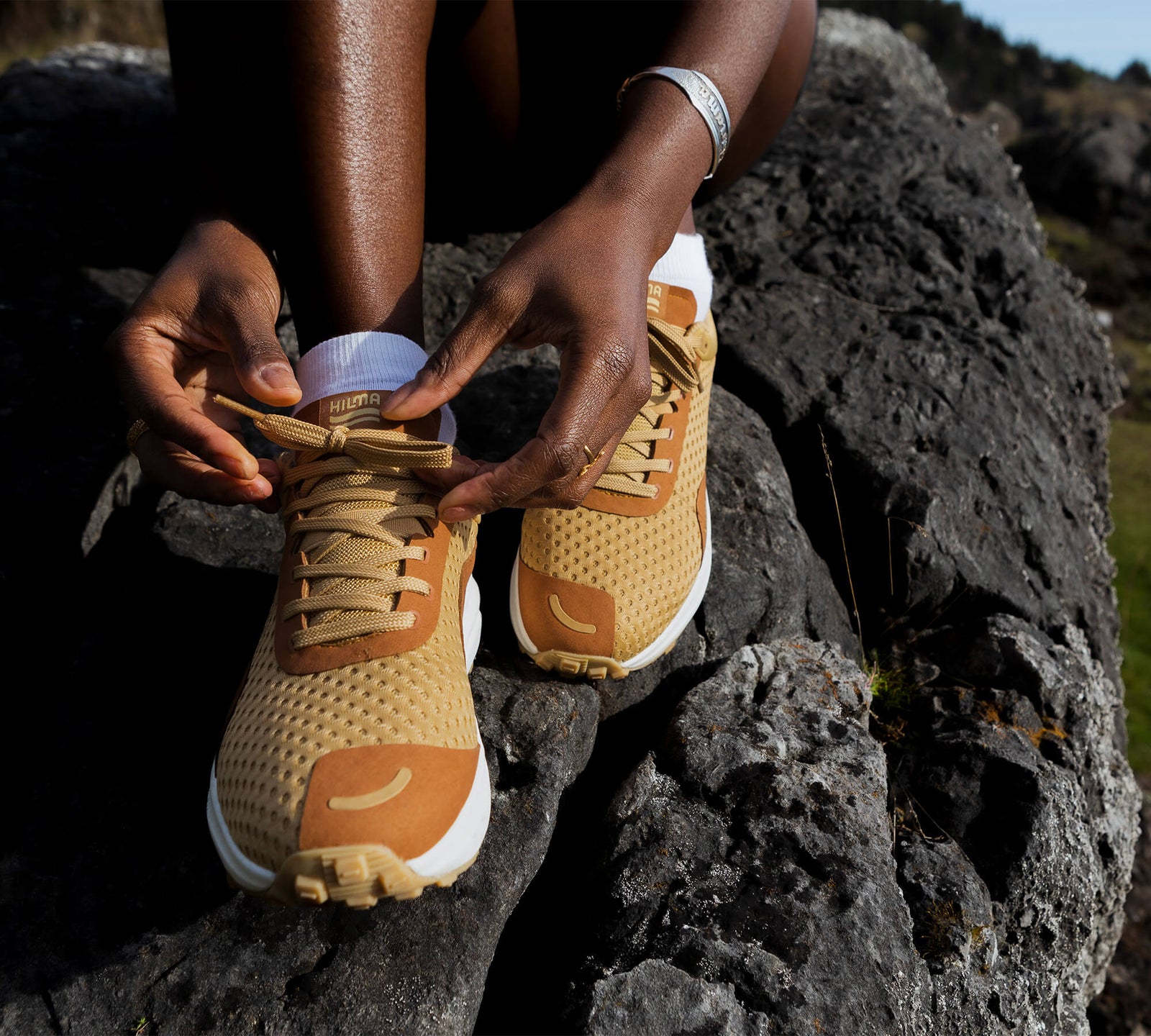 Person tying a pair of the Everywhere Hilma Running Shoe in Sandstone 